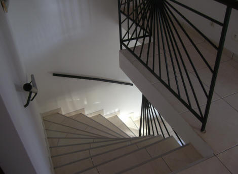 Escalier tournant en béton avec rampe en ferronnerie
